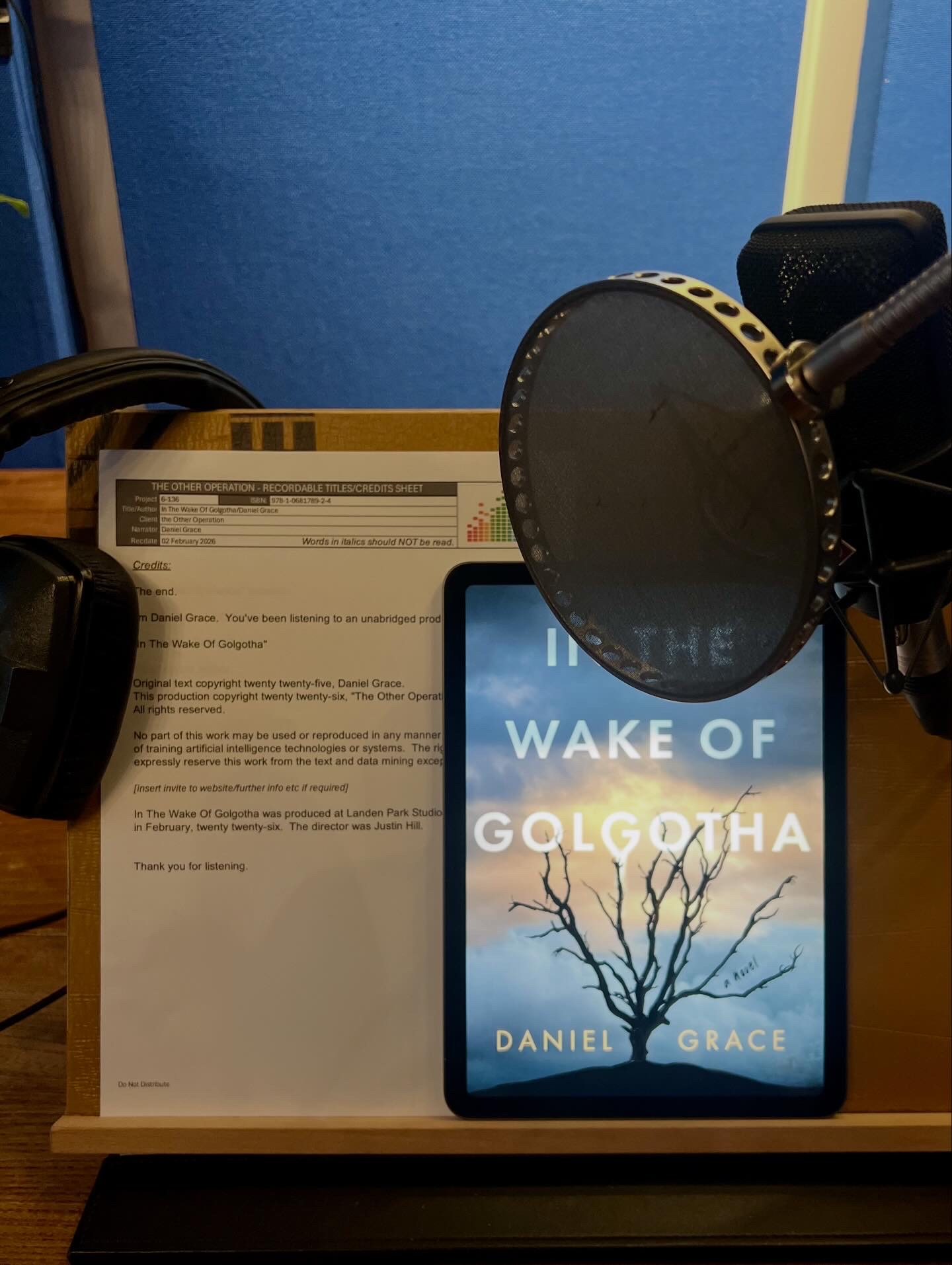Audiobook recording session — credits sheet, mic, and In the Wake of Golgotha cover on tablet