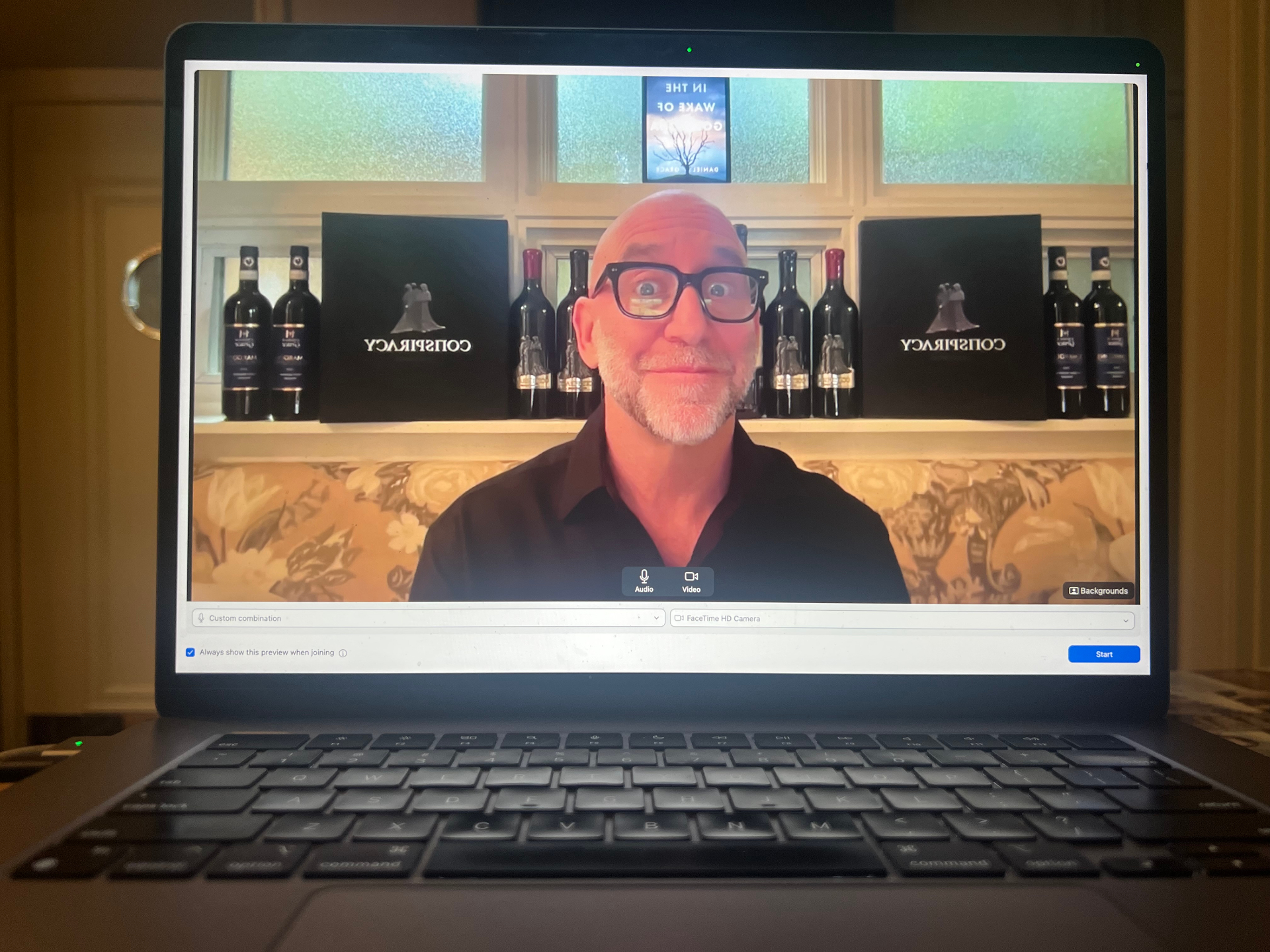 Daniel Grace on a virtual interview with Conspiracy wines and the novel framed behind him